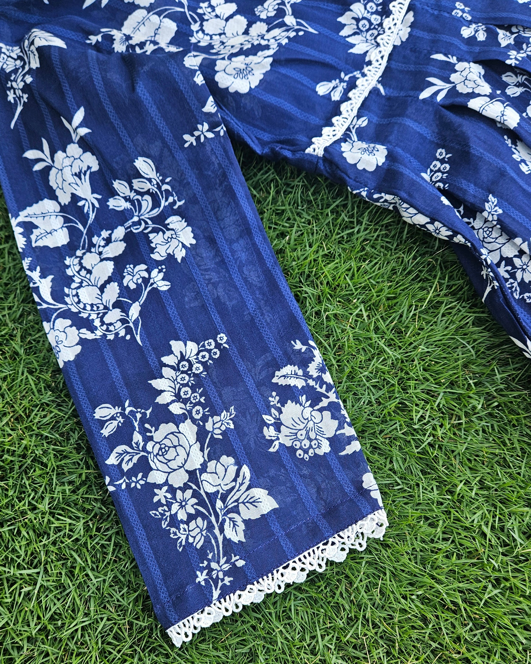 Blue fabric with white floral patterns on a grassy background