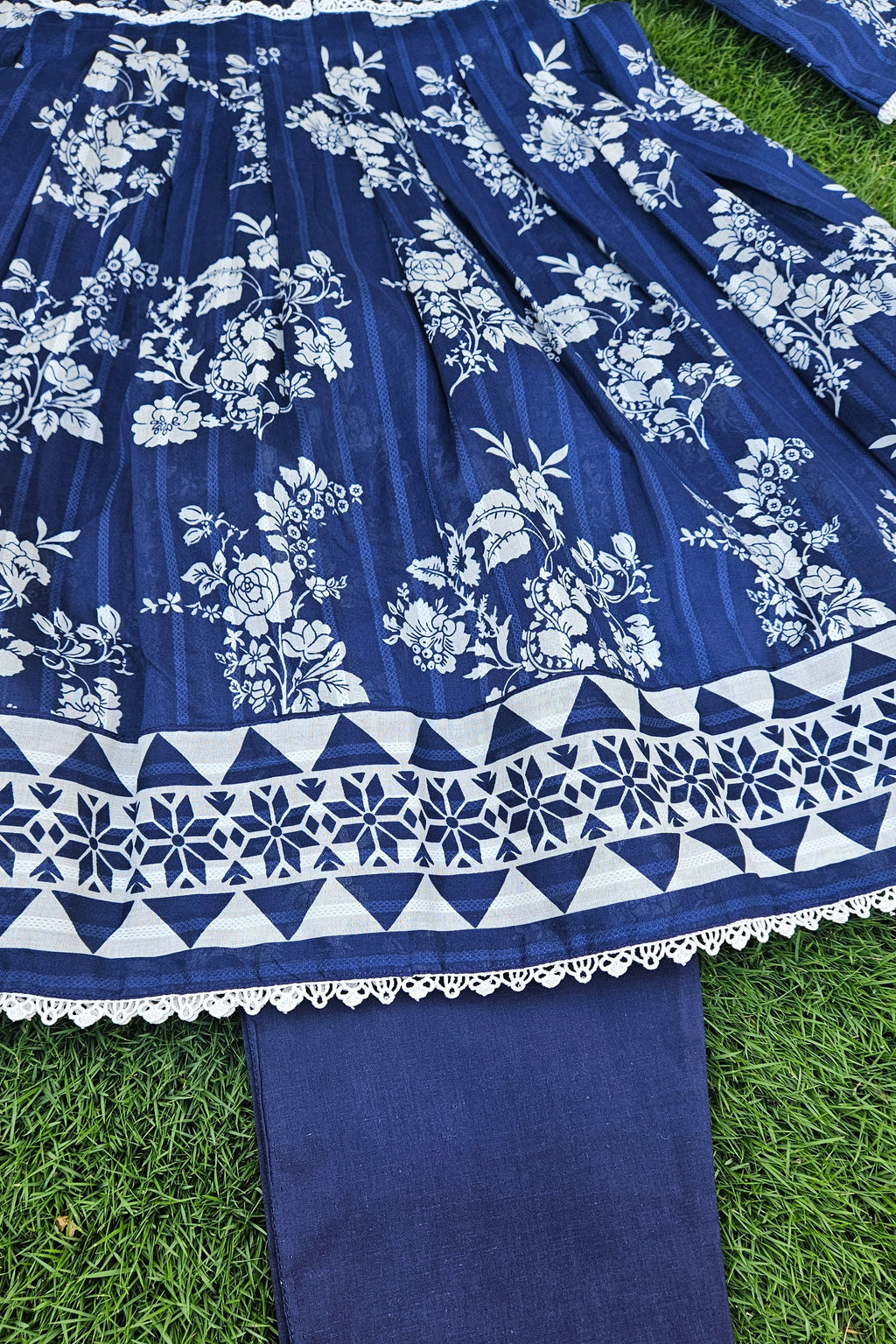 Blue fabric with white floral and geometric patterns on a grass background