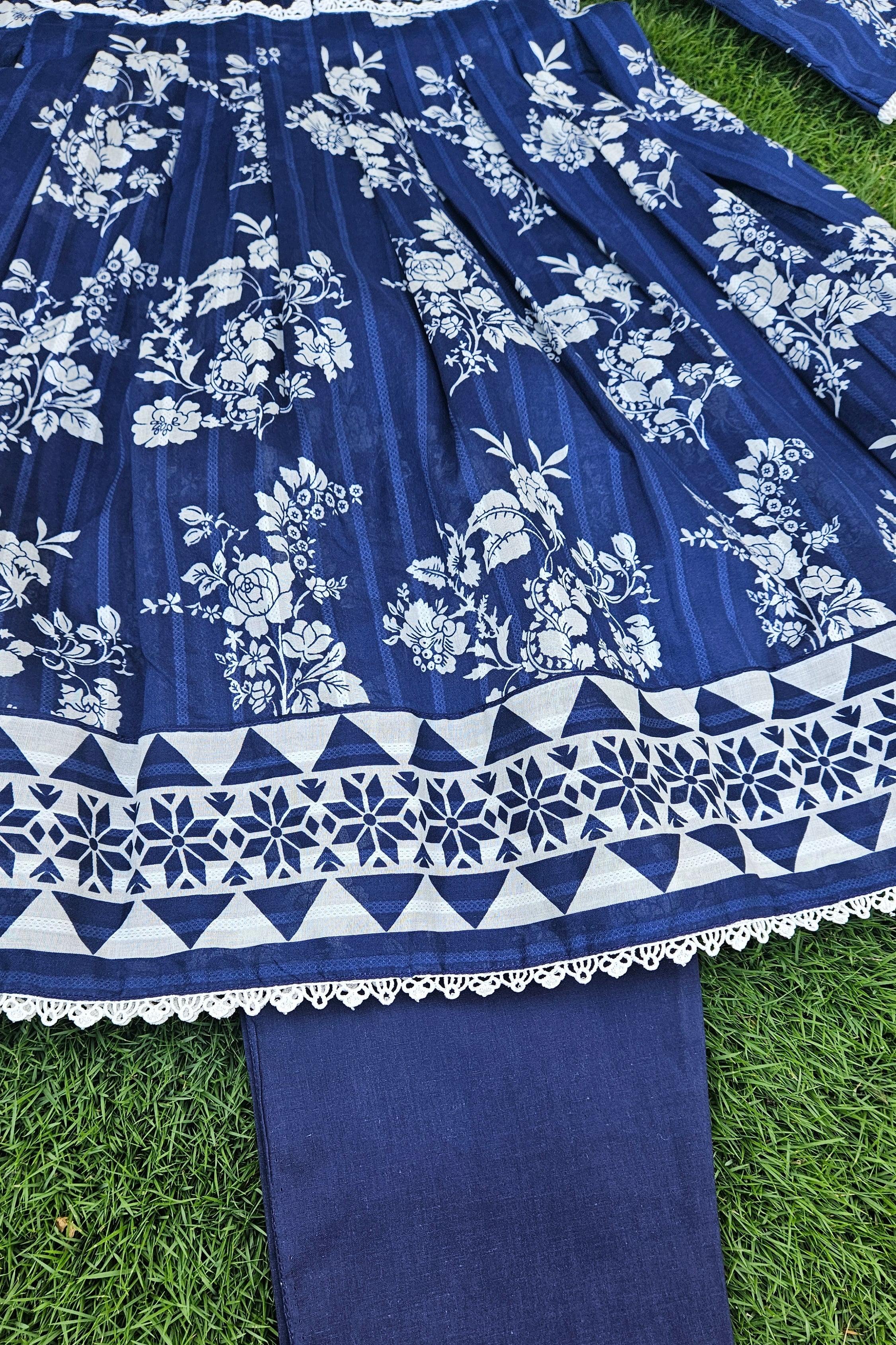 Blue fabric with white floral and geometric patterns on a grass background